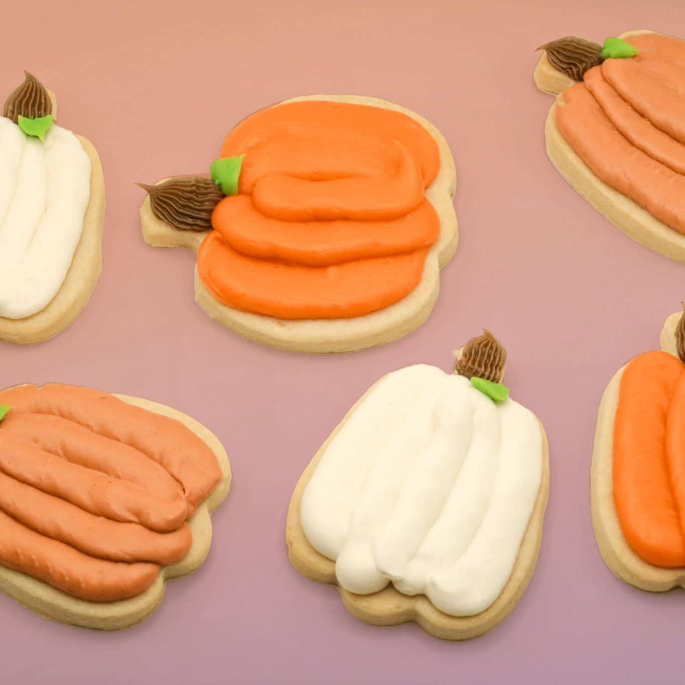 Decorative cookies shaped like pumpkins on a pink background
