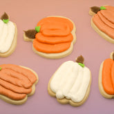 Decorative cookies shaped like pumpkins on a pink background